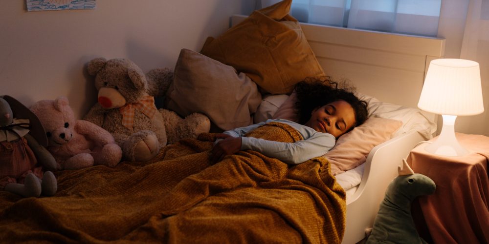 Kind ligt in bed met nachtlampje aan